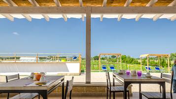 Eine Terrasse im Freien mit Tischen und Stühlen mit Blick auf Strand und Pool.