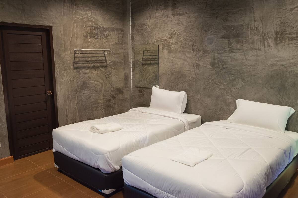 A room with two beds, a door, and a towel rack.