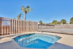 Ein Pool mit Holzzaun und einem 'No Diving'-Schild, umgeben von Palmen.