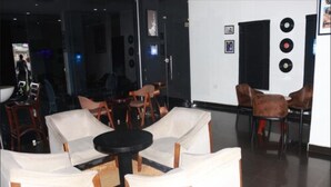 Un vestíbulo con asientos blancos acolchados, una pequeña mesa redonda y una pared decorada con discos de vinilo.