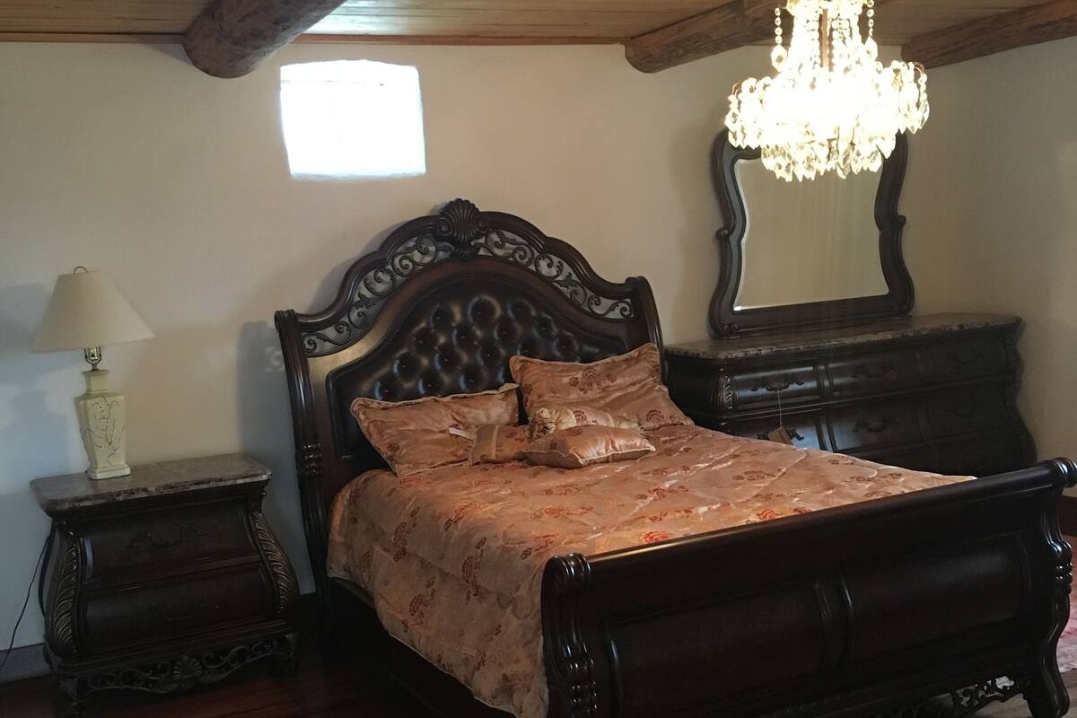 A wooden bed with a floral bedspread in a room with wooden flooring and a wooden ceiling.