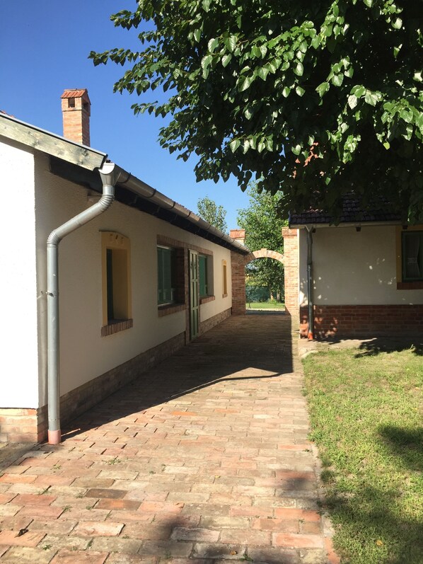 A pathway leading to a building with a brick facade and a chimney.