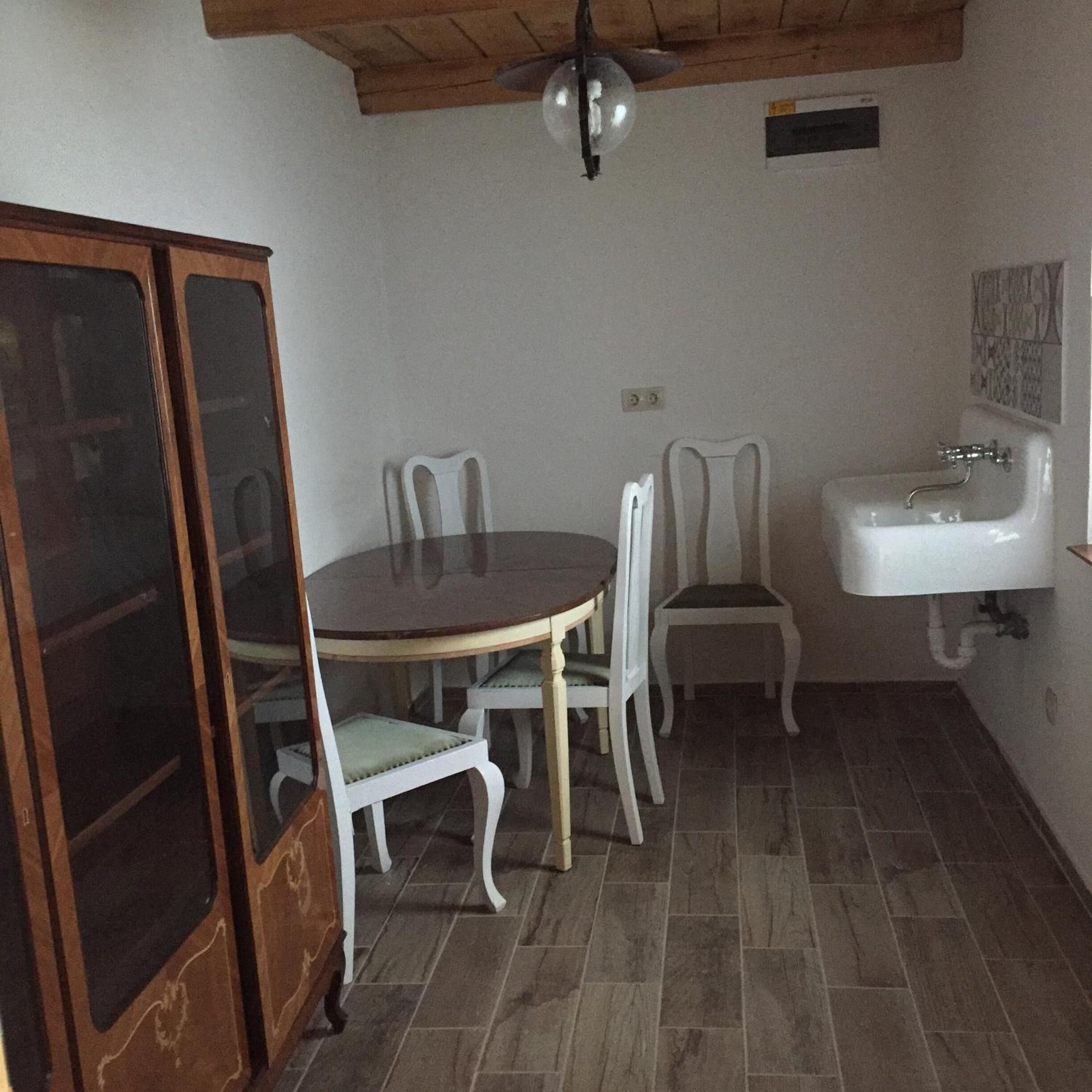 Una cocina compacta con mesa, sillas, un armario y un lavamanos.