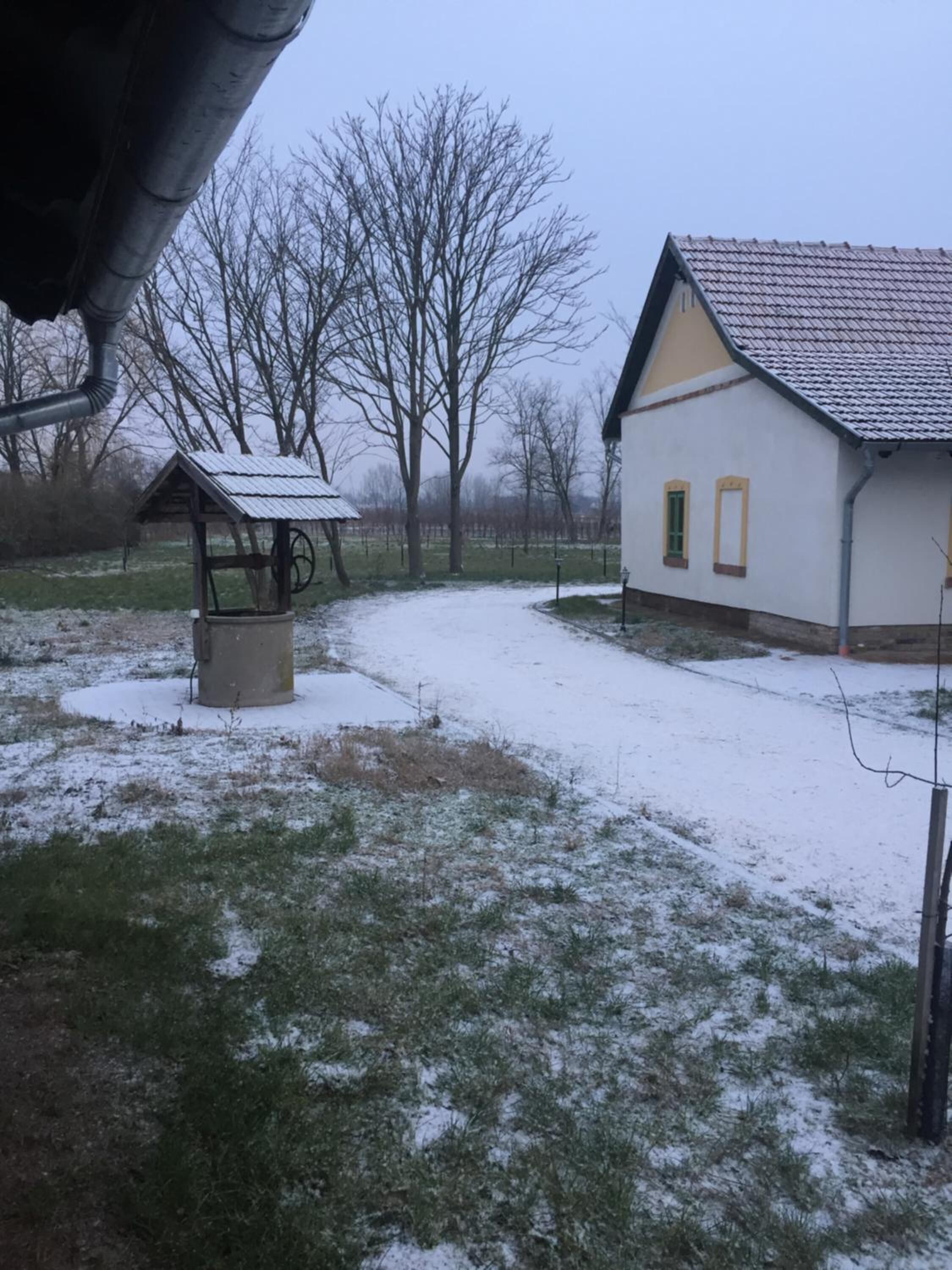 Een besneeerd landschap met een wit gebouw, voorzien van een pannendak en een klein bijgebouw met een metalen dak.