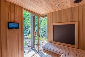 A sauna room with wooden walls, a bench, and a control panel. - LUXURY LOG CABIN WITH MOUNTAIN VIEW | HOT TUB (Cleveland)