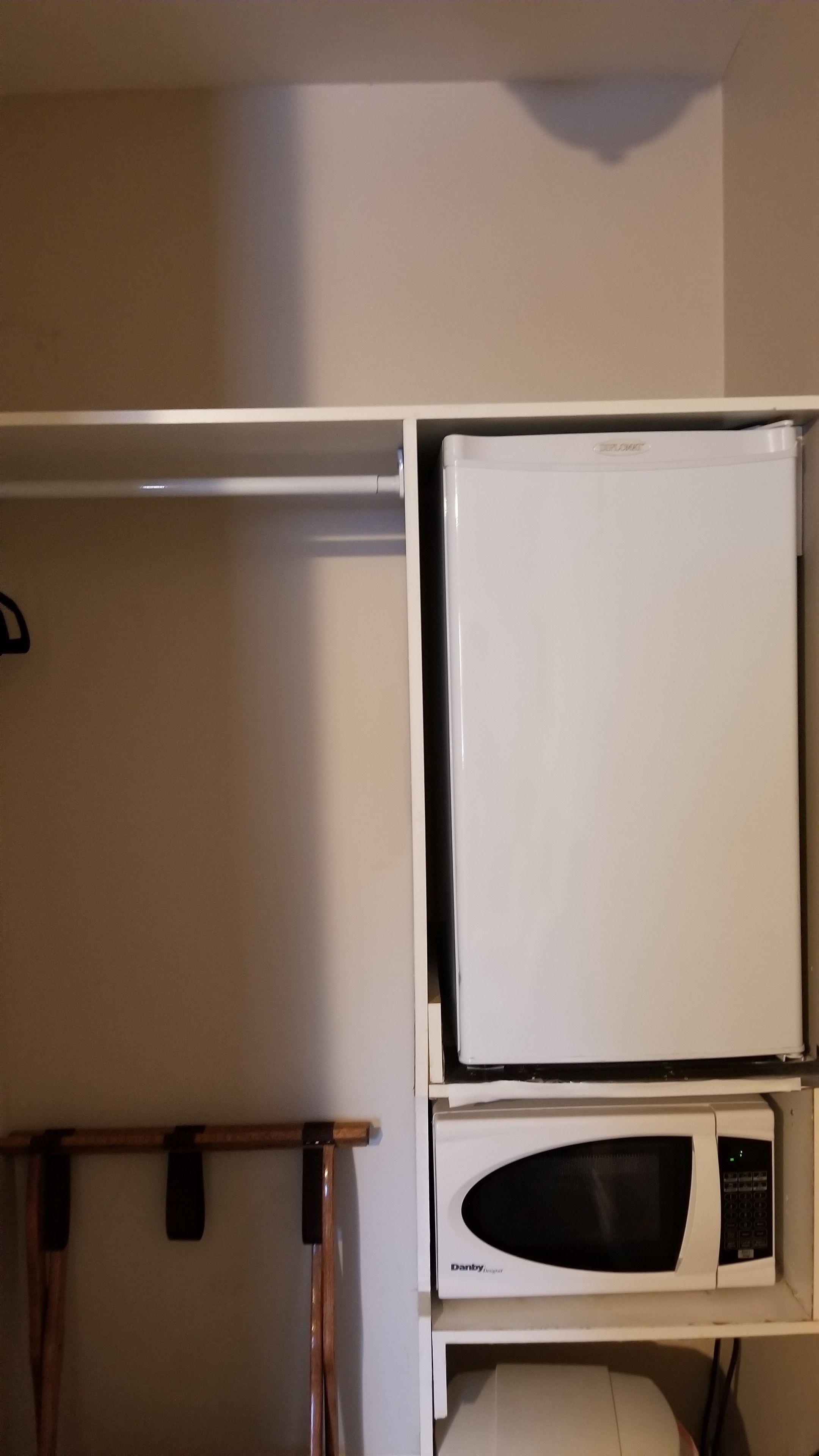 Un four à micro-ondes blanc est posé sur une étagère blanche dans une cuisine.