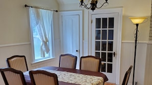 A dining room with a wooden table, four chairs, a chandelier, and a floor lamp. - Rothesay Motel (Rothesay)