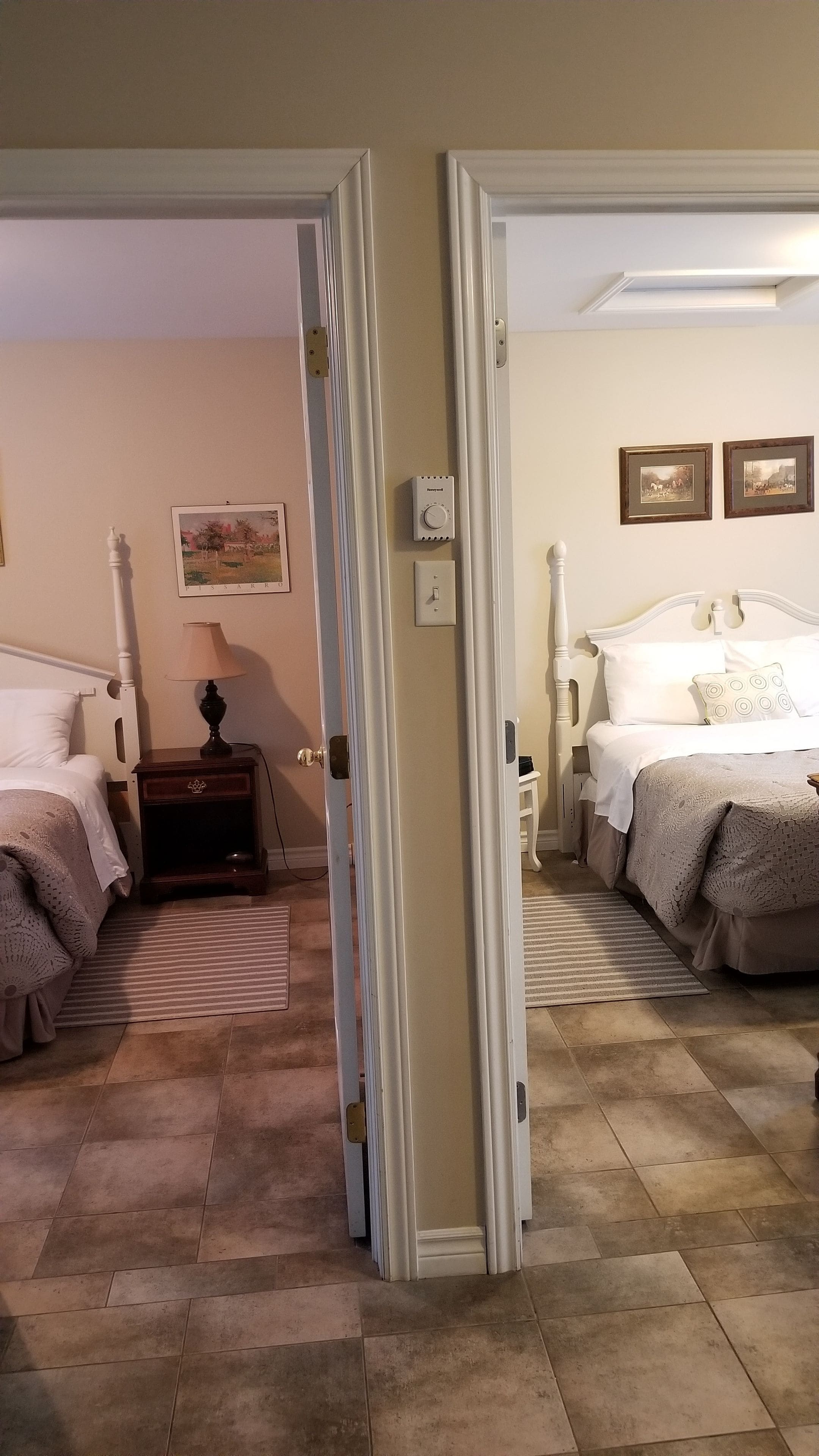A hotel room with a bed, bedside table, lamp, and a painting on the wall.