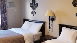 A hotel room with two beds, a wall-mounted air conditioner, a decorative wall piece, a wall-mounted lamp, and a curtain. - Rothesay Motel (Rothesay)