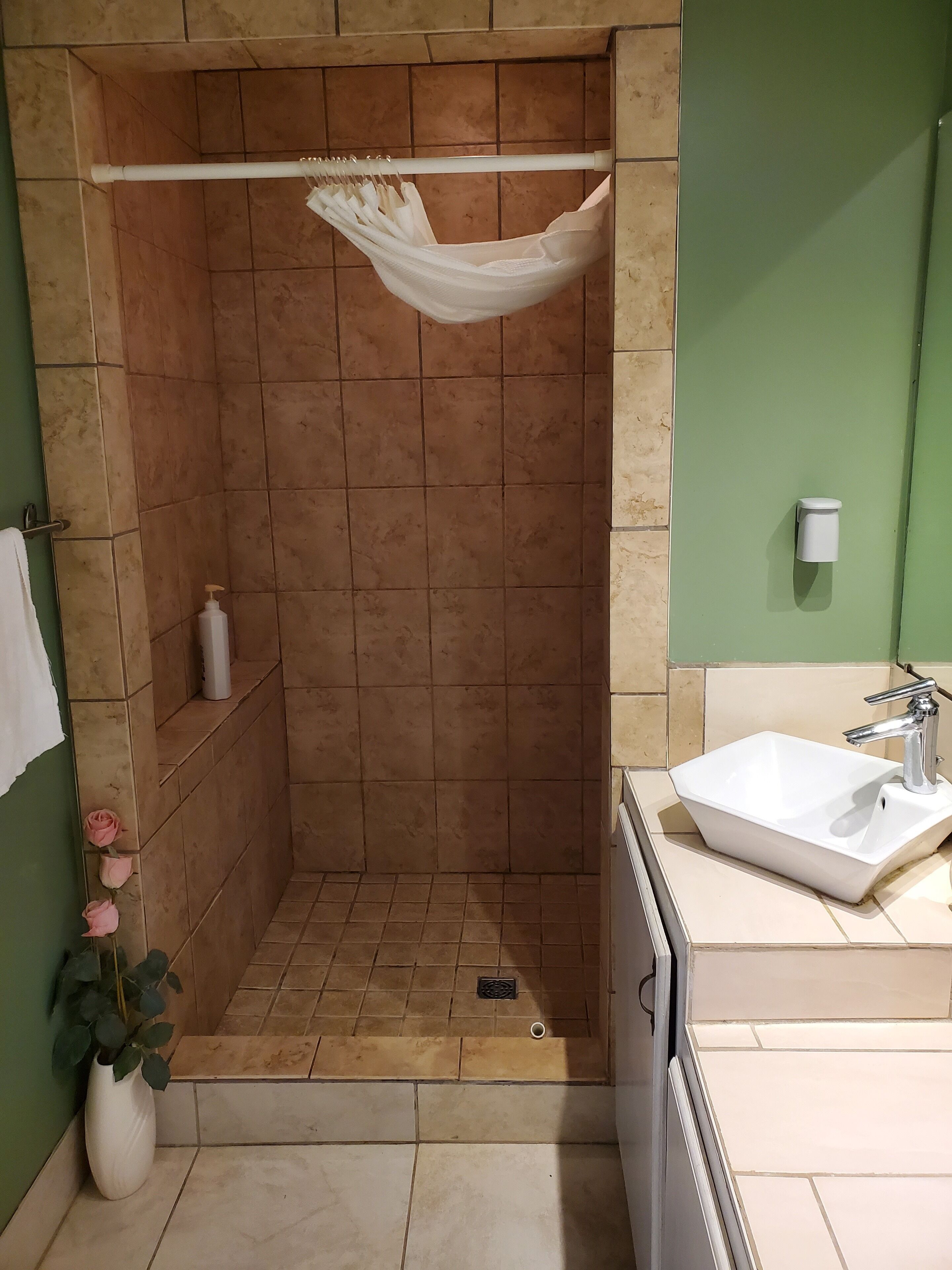 Un baño con zona de ducha, lavamanos e inodoro.