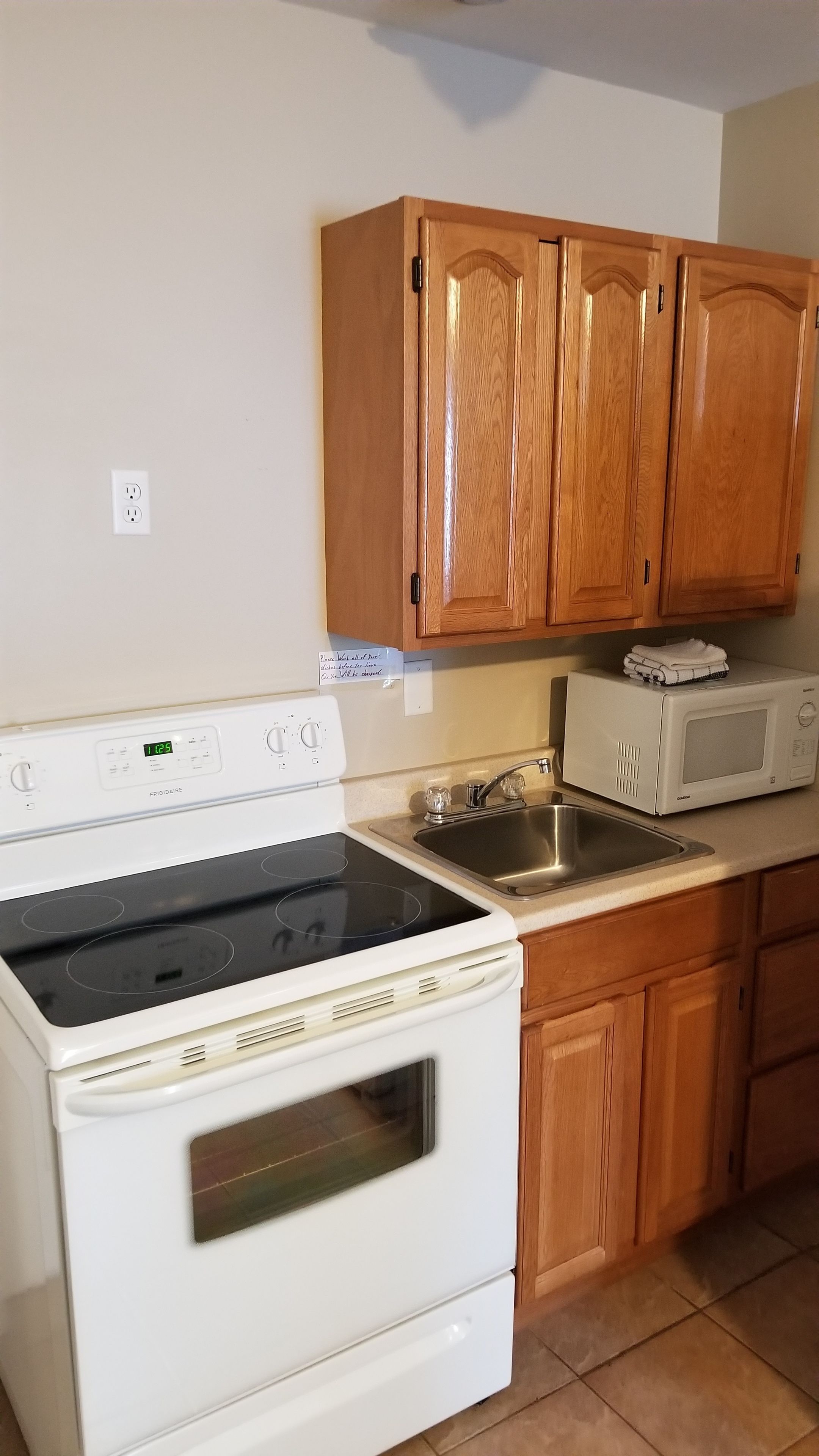 Une cuisine avec des meubles de rangement en bois, une cuisinière blanche, un four à micro-ondes et un évier.