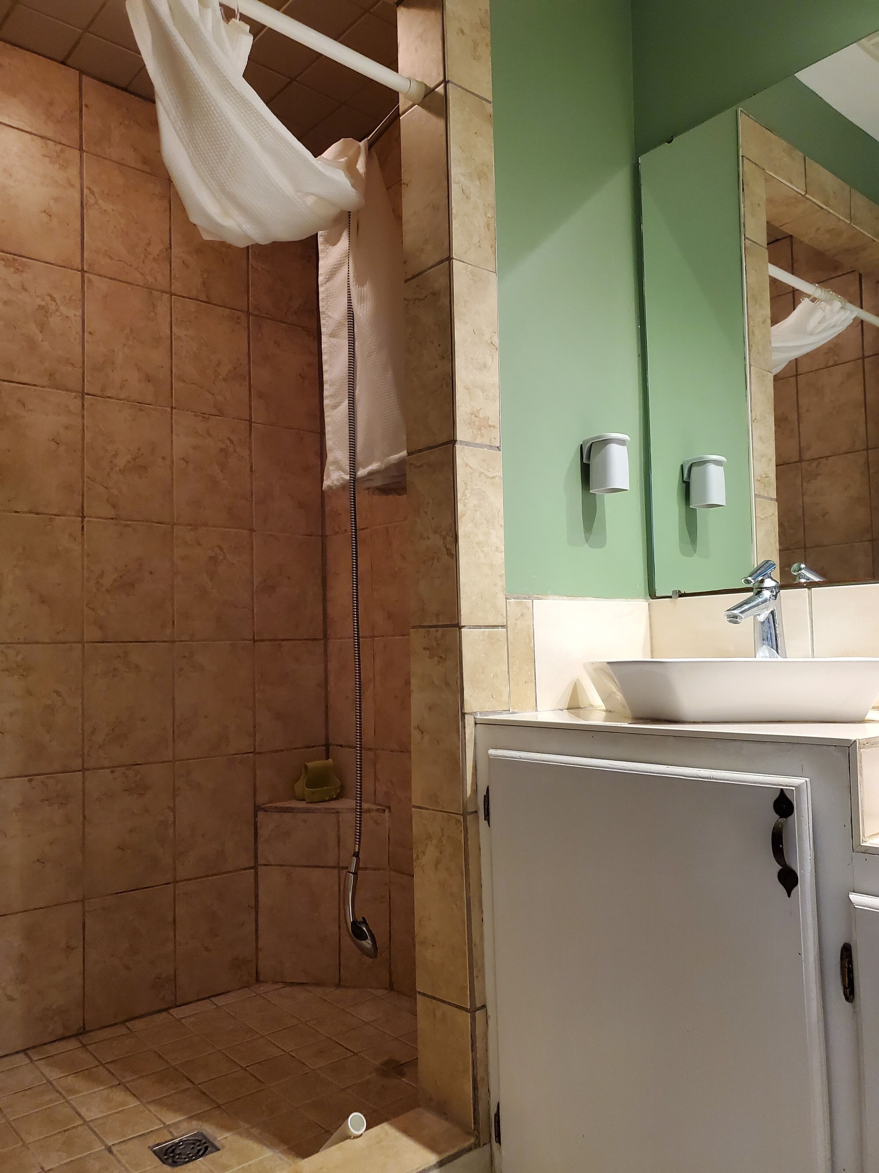 Baño con ducha, lavamanos y espejo.