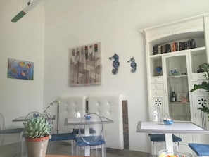 Un coin repas comprenant une table et des chaises, une plante en pot, une bibliothèque et des éléments de décoration murale.