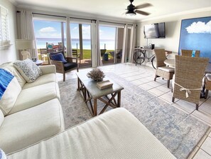 Relax in style with a spacious living area featuring a sofa, coffee table, and wicker chairs, perfect for taking in the ocean view from the adjacent balcony.
