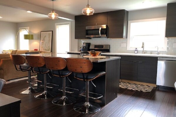 A modern kitchen with dark cabinetry, stainless steel appliances, and a central island with bar stools.