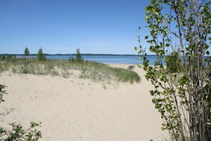A beach with sand, sparse vegetation, and a clear view of the water. - Walking distance to downtown Elk Rapids, Elk Lake and dining (Elk Rapids)