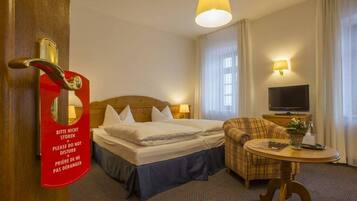 Una habitación de hotel con cama, sofá, televisor y una mesa con lámpara.