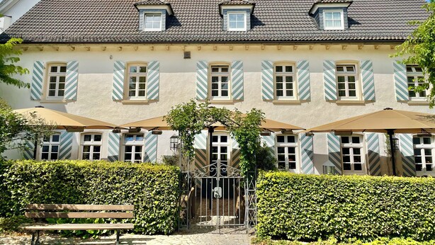 A two-story building with a tiled roof, multiple windows with shutters, and a gated entrance. - Landhotel Donner (Meschede)