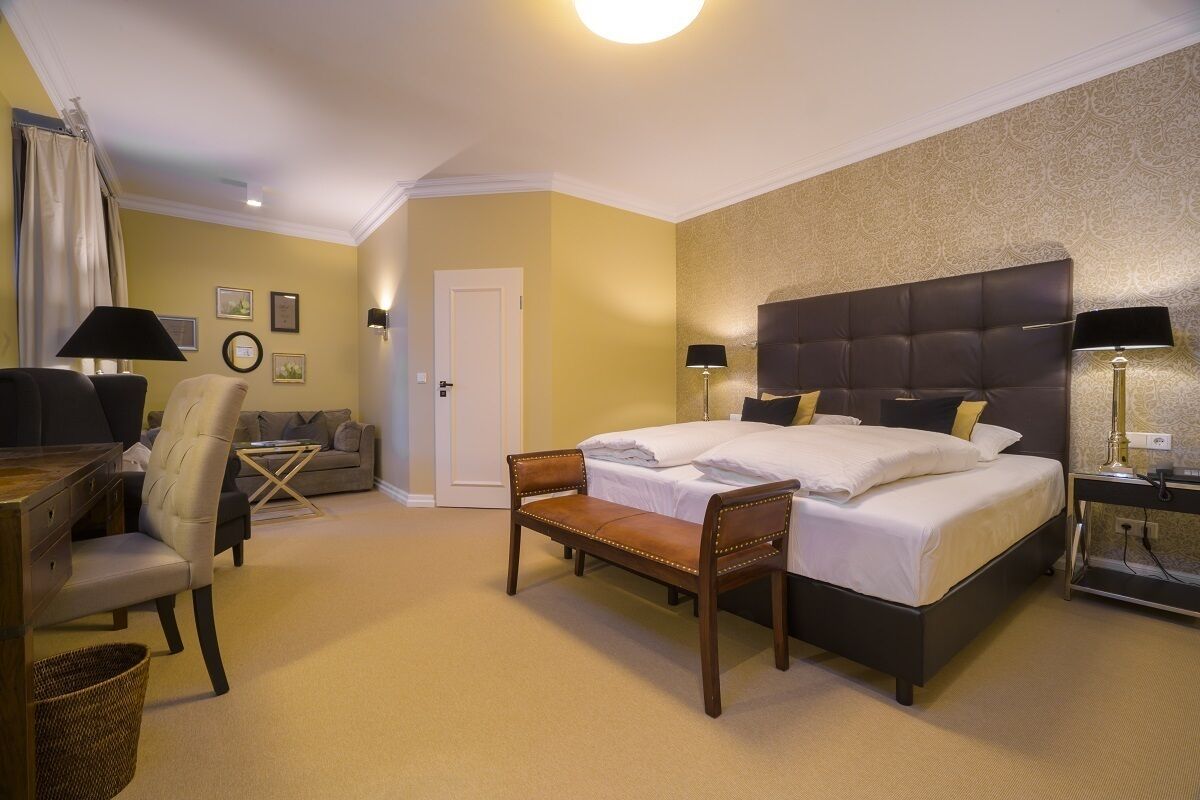 A hotel room with a large bed, a desk, a chair, and a sofa.