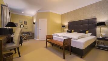 A hotel room with a large bed, a desk, a chair, and a sofa.