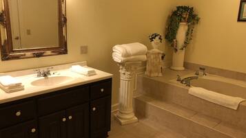 Un baño con tocador de doble lavabo, un espejo grande, una bañera y plantas decorativas.