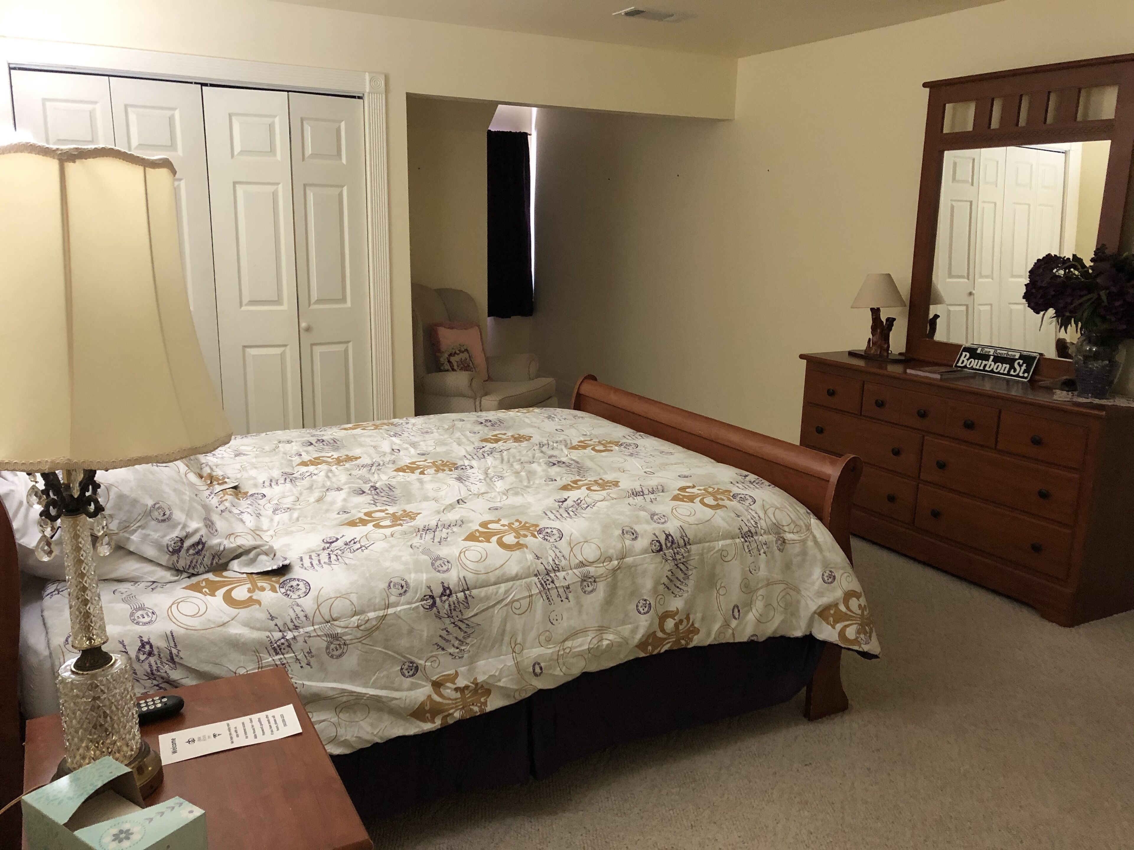 A bedroom with a bed, dresser, lamp, and a mirror.