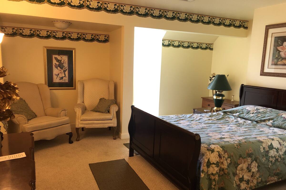 A bedroom with a bed, a chair, a desk, and a lamp.