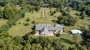 An aerial view of a large house with a spacious lawn, a driveway, and a garage.