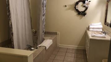 A bathroom with a bathtub, a shower curtain, a sink with a mirror, and a towel rack.