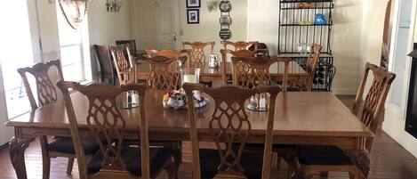 A dining room with a wooden table and chairs, a chandelier, and a decorative metal rack with vases.