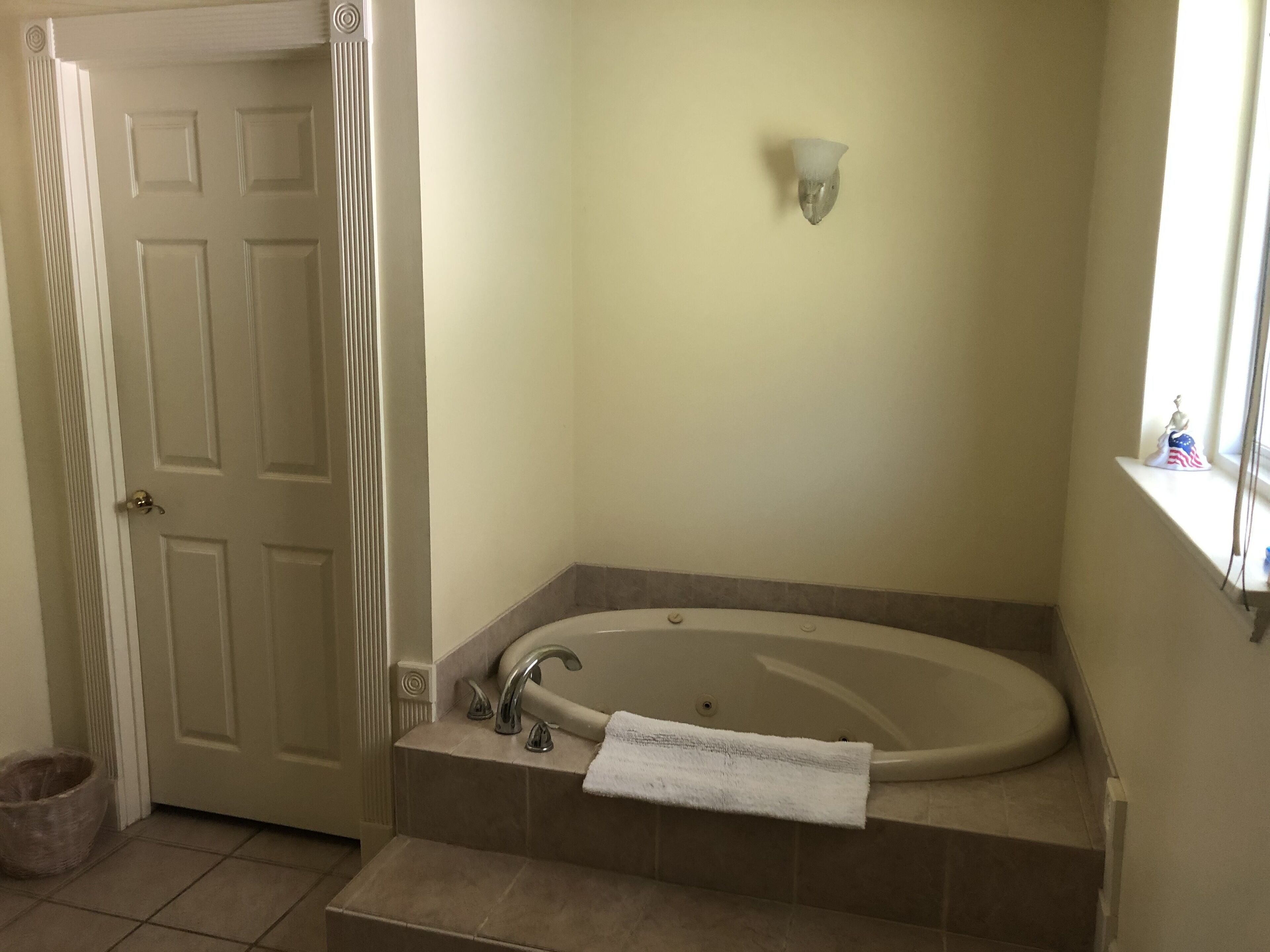 A bathroom with a freestanding bathtub, a towel rack, and a window with a decorative item.
