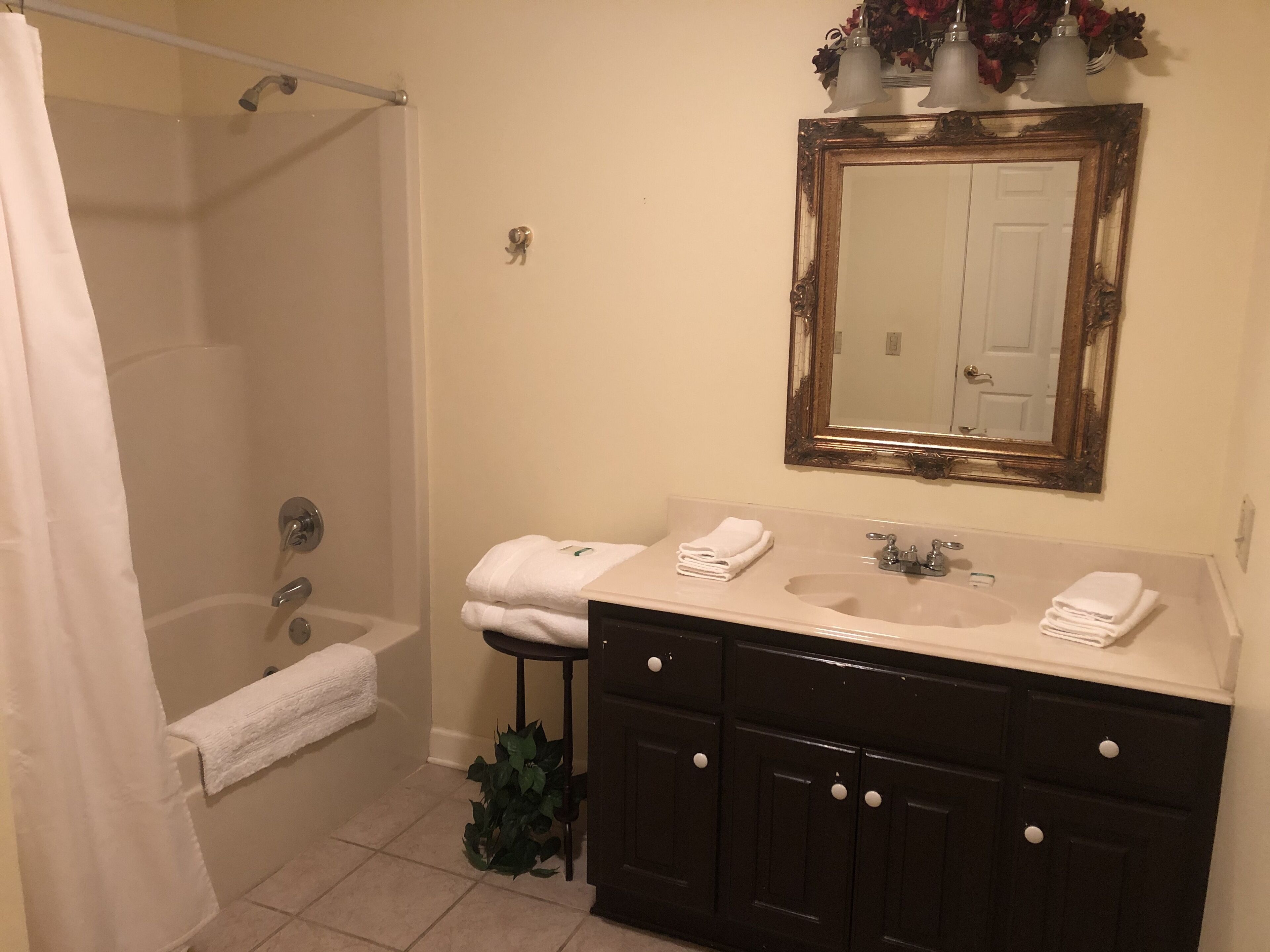 A bathroom with a bathtub, a sink, a mirror, and a shower curtain.