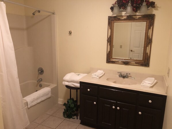 A bathroom with a bathtub, a sink, a mirror, and a shower curtain.