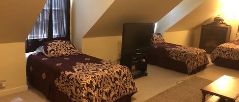 A bedroom with two beds, a TV, and a small table.