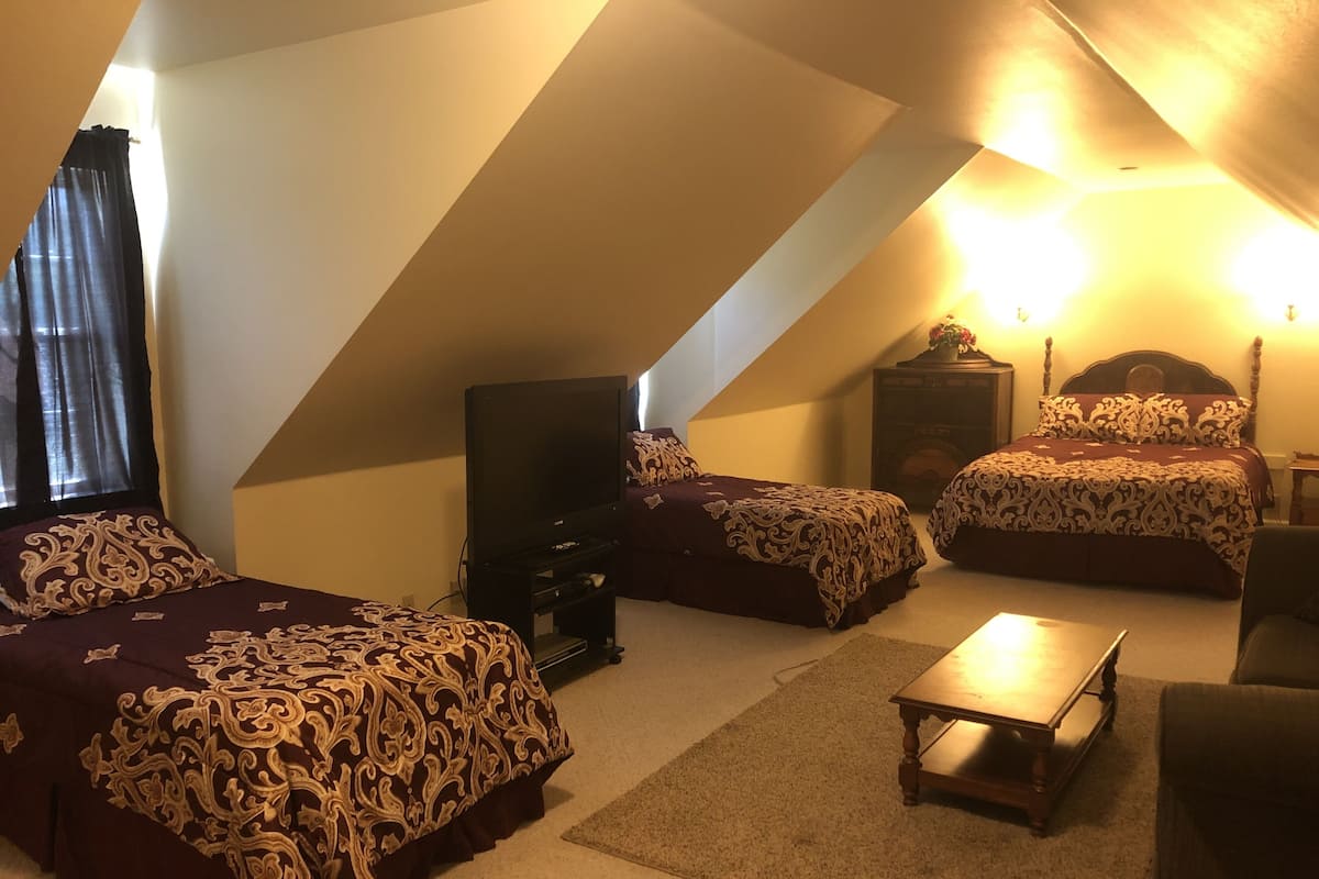 A room with two beds, a TV, a small table, and a chair.