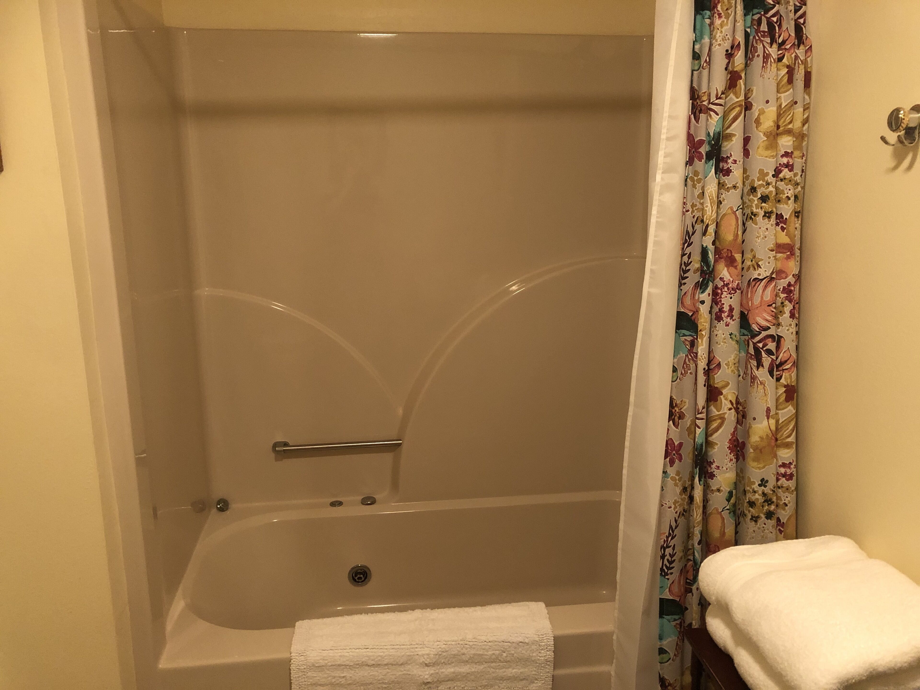 A bathroom with a bathtub, a shower curtain, and a towel.
