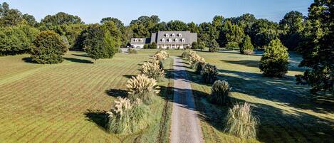 A large, modern house with a symmetrical design, surrounded by a well-maintained lawn and trees.