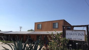 A two-story building with a sign for Leakey Inn, featuring a vintage design and a contact number.