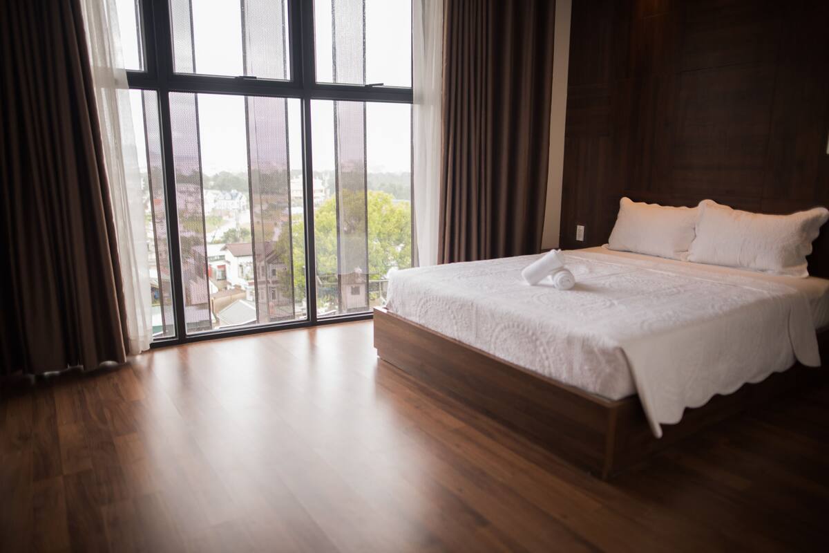 Un dormitorio con un ventanal grande, una cama de madera y vistas al exterior.