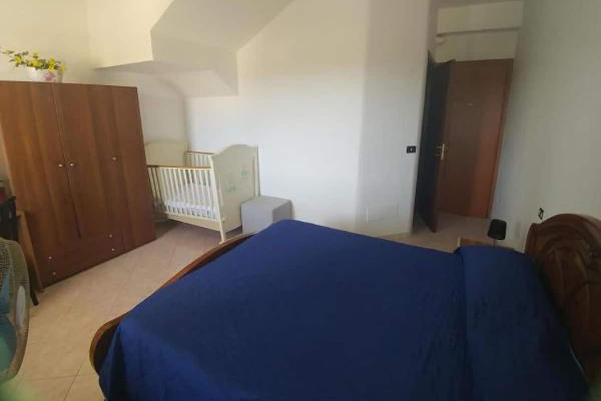 Un dormitorio con cama, cuna, armario y puerta que da a otra habitación.