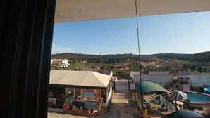 A view from a window overlooking a pool area with a clear sky and distant hills. - B&B Iafrate Daniele (Priverno)