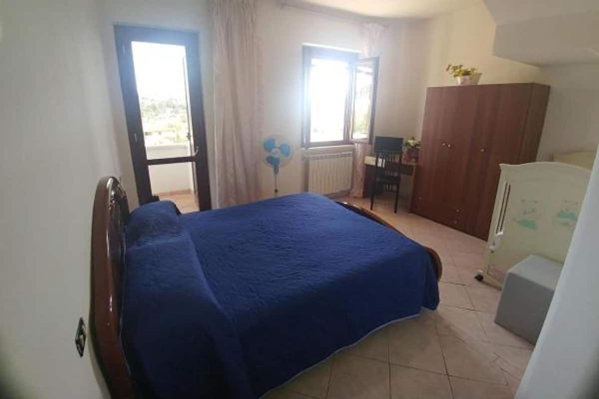 Un dormitorio con cama, escritorio, armario y radiador.