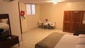 Une chambre d’hôtel comprenant un lit, un bureau, une chaise, une petite table et une armoire.
