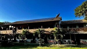 Een gebouw met een schuin dak, zonnepanelen en een gevel van natuursteen.