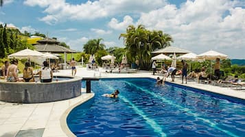 Una piscina techada, una piscina al aire libre, sombrillas