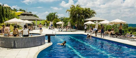 Una piscina techada, una piscina al aire libre, sombrillas