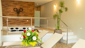 Ein moderner Poolbereich im Innenbereich mit Liegestühlen, einer Treppe und einer Holzverkleidung.