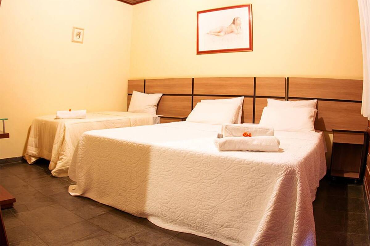 Ein Hotelzimmer mit zwei Betten, jeweils mit einem Holz-Kopfteil und weißer Bettwäsche.