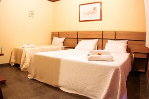 Habitación de hotel con dos camas, cada una con cabecero de madera y ropa de cama blanca.