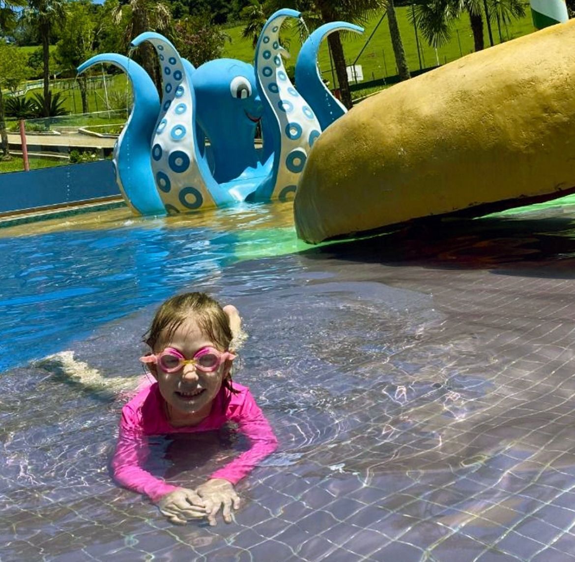 A child in a swimming pool with a slide and inflatable octopus decorations.